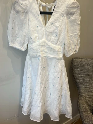 Vit blommig kortklänning Gina Tricot - Supersöt vit kortklänning från Gina Tricot med små blå blommor, puffärmar och öppen rygg med knyt. Tillverkad i ett lätt bomullstyg, perfekt för varma dagar. Volangkant nertill och smock i midjan för en bekväm passform. Jätte fin till en sommar dag!!!!❤️.                                        Köpte denna för 599 kr men ni får den för 150. Denna klänningen finns inte kvar från ginatricot längre så den är värd!🙌🏽