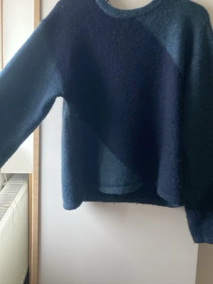 Mörkblå stickad tröja Gina Tricot - Mysig mörkblå stickad tröja från Gina Tricot i storlek 170. Tröjan har en enkel, rak passform med rund halsringning och långa ärmar. Perfekt för kyliga dagar och enkel att matcha med jeans eller kjol.