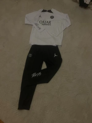 PSG Träningsset - Säljer PSG tränings tracksuit: 	•	Träningsjacka/tröja 	•	Byxor  Perfekt för sport, gym eller vardag.  ✅ Bra skick ✅ Officiell PSG-produkt ✅ Sportig & stilren  📩 Hör av dig vid intresse.