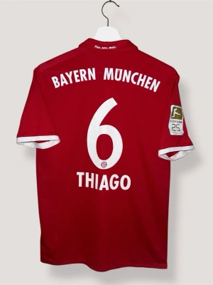 Bayern München 17/18 Hemma - #6 Thiago - adidas fotbollströja - storlek M  - 𝐁𝐚𝐲𝐞𝐫𝐧 𝐌𝐮𝐧𝐜𝐡𝐞𝐧 𝟏𝟔/𝟏𝟕 Bayern Münchens hemmatröja för säsongen 2016/17 har klubbens ikoniska helröda design med subtila horisontella ränder för en modern touch. Med Thiagos namn och nummer 6 på ryggen hyllar den den spanske mittfältarens elegans och intelligens under en titelvinnande säsong under Carlo Ancelotti 🔴⚪️  Skick: 9/10. Utmärkt skick. Inga defekter! ✅  Storlek: M  Låt mig veta om du har några frågor eller andra funderingar!