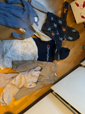 Set pojke  par två byxor fem tröjor  Champion hoodie med huva - Det du ser! Säljer en mörkblå hoodie från Champion stor logga framtill. Tröjan har huva . En har  ribbade muddar amung us figurer samt en stor ficka framtill. två tröjor i stickat en blå  material . Stl 122-132 Allt i fräscht fint skick inga hål fläktar osv ! Perfekt skick . Konta mig gärna innan köp ! ☀️🫶