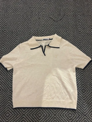 Beige kortärmad polotopp med krage - En cremefärgad poli tröja i mjukt material. Använd en gång.