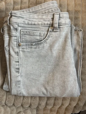 Ljusgrå jeansbyxor i storlek 36 - Då Säljer jag ett par ljusgrå jeansbyxor i klassisk femficksmodell som har blivit för små för mig!  Byxorna har flare legs och normal passform, tillverkade i mjukt jeanstyg. De är ett par lågmidjade Perfekta för dig som gillar en clean och enkel look.