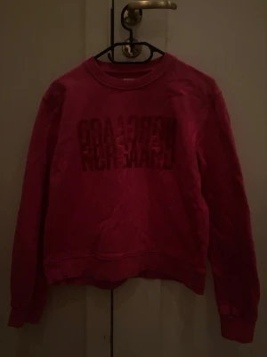Rosa sweatshirt från Nørgaard - Cool rosa sweatshirt från Mads Nørgaard med tryckt logga framtill. Klassisk rund halsringning och långa ärmar. Perfekt för dig som gillar streetwear och vill ha en färgklick i garderoben.
