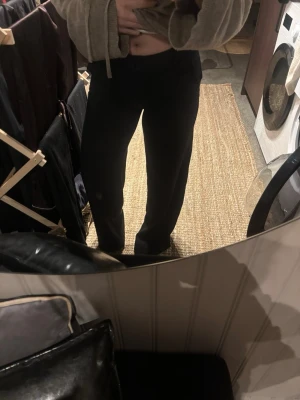 Svarta kostymbyxor med raka ben från Gina tricot  - Säljer ett par svarta kostymbyxor med raka ben och bälteshällor. Byxorna har en klassisk look med dragkedja och knapp framtill. Passformen är normal och materialet känns mjukt och följsamt, perfekt till en snygg outfit.