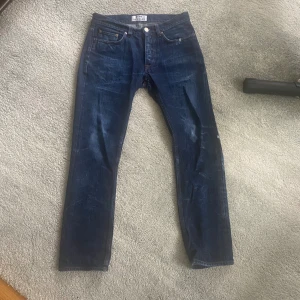 Mörkblå jeans från Acne Studios - Säljer ett par mörkblå jeans från Acne Studios med klassisk femficksdesign och raka ben. Jeansen har normal passform och är tillverkade i slitstarkt bomullsmaterial. Snygga kontrastsömmar och diskret tvättad look för en stilren vibe. Snygga slitningar. Storlek 30 som jag skulle säga motsvarar 30:30