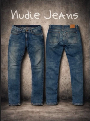Blå Nudie Jeans  - Säljer ett par klassiska blå jeans från Nudie Jeans med snygga slitningar och orangea sömmar. Jeansen har fem fickor, läderpatch bak och är tillverkade i mjukt denimtyg. Perfekta för dig som gillar en tidlös stil. Storlek W33 och L32