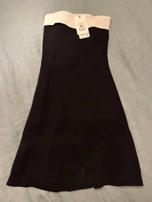 Svart axelbandslös kortklänning - Aldrig använd! Figursydd ärmlös klänning från bil bok 