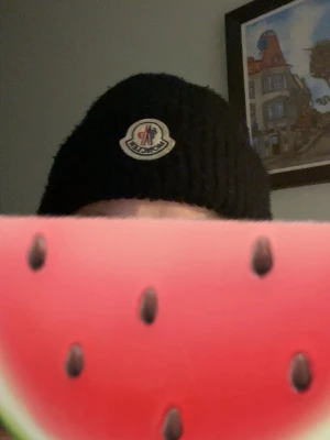 Svart Moncler mössa i ull - Säljer en svart ribbstickad mössa från Moncler med klassisk logotyp framtill. Mössan är i mjuk ull och har en uppvikt kant för extra stilpoäng. Perf soppa till kalla dagar och snygg till alla outfits.