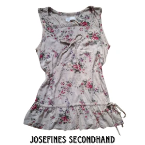 Söt blommig coquette blus - Beige ärmlös blus i blommigt mönster med rosetter. Det går att justera storleken på kragen ich midjan med snörena. Använd gärna köp nu/prisförslag funktionen