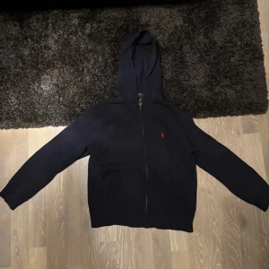 Blå hoodie från Ralph Lauren - Säljer en stilren marin blå hoodie från polo Ralph lauren, sällan använd. Om det är några frågor är det bara att höra av sig.😁