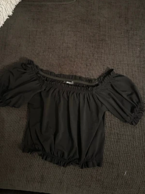 Svart offshoulder topp Gina Tricot - Säljer en svart offshoulder topp från Gina Tricot i storlek S. Toppen har puffiga korta ärmar och resår vid axlar, ärmslut och nederkant för en snygg passform. 