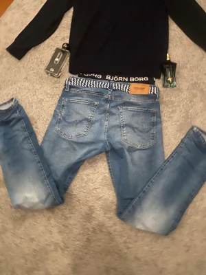 Blå jeans från Jack & Jones, 27/30 - Säljer ett par ljusblå jeans från Jack & Jones i storlek 27/30. Jeansen har klassisk femficksdesign, normal passform och raka ben. Materialet är jeans i bomull och de har snygga slitningar och tvättade detaljer för en avslappnad look. Lappen där back är lätt sönder men går att sy fast jätte enkelt modell 165 isch