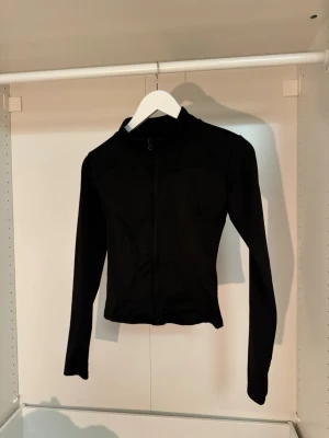 Svart croppad ziptröja - Träningströja. Snygg svart croppad ziptröja med lång ärm och hög krage. Tillverkad i ett stretchigt material som sitter tajt och ger en sportig look. Perfekt att matcha med jeans eller kjol för en trendig outfit. Står ej storlek men uppskattar XS💞