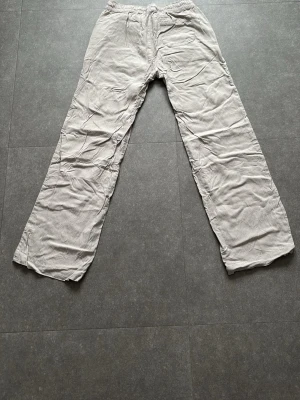 Beiga linnebyxor med resårmidja - Säljer ett par beiga linnebyxor från 157 med avslappnad passform och resår i midjan. Byxorna har sidfickor fram och en bakficka. Perfekta för chill dagar och riktigt sköna tack vare det tunna linnematerialet.