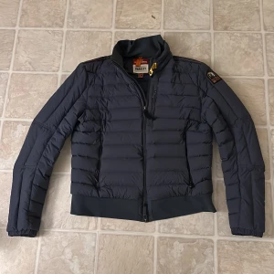 Parajumper jacka  - Superskön vår/höst jacka strl L sitter mer som M/L blev ett litet hål i jackan men som nu är täckt. (Syns knappt) (se bild). Det finns fläktande hål i armhålhålorna (se bild). Såklart äkta, det är bara att skanna QR-koden så ser man det. Kan hoppa vid pris vid snabb affär 