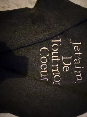 Mörkgrå stickad tröja Gina Tricot - Mysig mörkgrå stickad tröja från Gina Tricot med broderad text framtill. Tröjan har rund halsringning och långa ärmar, perfekt för kyligare dagar. Enkel att matcha med jeans eller kjol för en chill look.