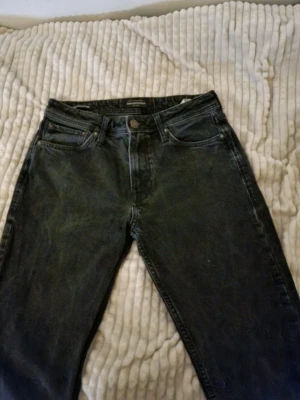 Svarta jeans från Jack & Jones - Säljer ett par svarta jeans från shade 'Jeans Intelligence' av Jack & Jones. Klassisk femficksmodell med raka ben och normal passform. Jeansen har en snygg tvättad look och är tillverkade i bomull. Perfekta till en avslappnad stil.