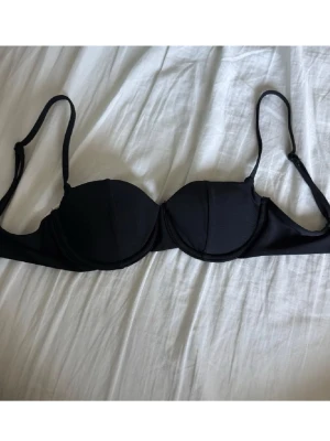 Svart bikiniöverdel med bygel - En stilren svart bikiniöverdel med bygel och justerbara axelband. Klassisk form med vadderade kupor och enkel knäppning bak. Den är från Gina tricot men jag klippte av lappen då den stördes vid användning, använt 2 gånger❤️reupload då det är fri frakt 😊