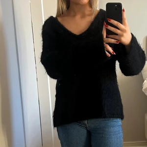 Svart fluffig stickad tröja v-ringad - Din srixksd tröja med v ringning, aldrig använd. Polyamid 33%, Mohair 32%, Ull 32%, Elastan 3%