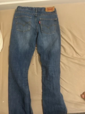 Levi's 511 blå jeans - Säljer ett par klassiska Levi's 511 jeans i blå tvätt. De har fem fickor, gul kontrastsöm och den ikoniska röda Levi's-lappen på bakfickan. Jeansen har en rak passform med något smalare ben och är tillverkade i slitstarkt denimtyg.