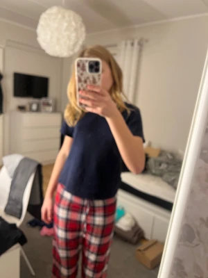 Rödrutiga mjukisbyxor med snörning - Rödrutiga mjukisbyxor från C i storlek 146/152. Byxorna har ett klassiskt rutmönster i rött, vitt och svart samt snörning i midjan för extra komfort. Perfekta för chill dagar hemma eller som mysplagg.