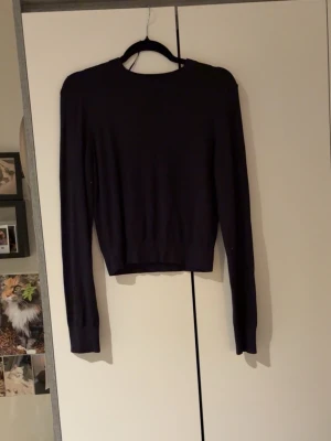 Mörkblå stickad tröja från H&M - Säljer en mörkblå stickad tröja från H&M i storlek S. Tröjan har rund hals, långärmade smala ärmar och ribbade muddar vid hals och ärmslut. Perfekt för lager-på-lager och enkel att matcha med jeans eller kjol.