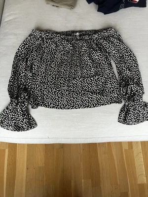 Shoulder-blus i boxig modell HM - Oanvänd fin off shoulder blus från HM i glansigt material. Det är en boxig modell och ganska kort i längden. Oanvänd. 