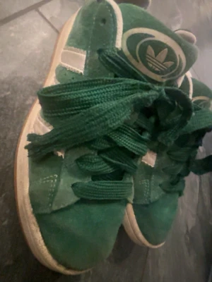 Adidas campus gröna  - Gröna Adidas campus sneakers med klassiska vita ränder och Adidas-logga på tungan. Skorna har breda gröna snören. har även vita nya snören och gröna till de💕💕