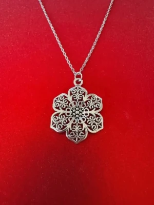 Halsband mönstrad blomma - Halsband skapat av mig och dottern.  Halsband som inte är i äkta silver/guld. Kedja är oftast 50cm men kan ibland komma i 45cm. Kedja är rostfritt stål, berlock oftast i zinklegering men kan även det i vissa fall vara rostfritt stål. Be gärna om mått på berlock om detta är viktigt då bilderna är missvisande när det gäller hur stora dom är! 🌹❤️  Allt är nytt även om de kan stå ”mycket bra skick” , detta mest för att Vinted inte ska fundera på varför jag bara har nya saker .  Bud accepteras inte 🥰🌹