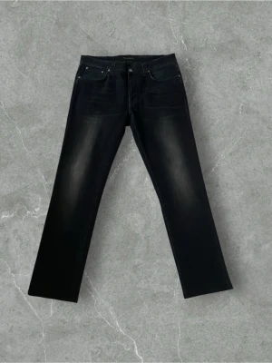 Svarta Nudie Jeans Lean Dean 36/36 - Säljer ett par svarta Nudie Jeans Lean Dean i storlek 36/36. Modellen har en slim passform med raka ben och klassisk femficksdesign. Materialet är 98% ekologisk bomull och 2% elastan för extra stretch. Snygg mörk tvätt med subtila slitningar.