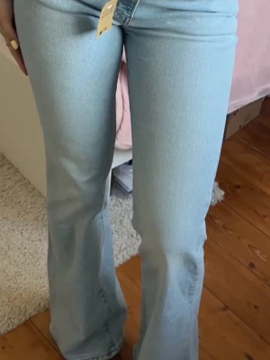 Levi's 517 bootcut jeans ljusblå - Säljer ett par Levi's 517 jeans i ljusblå tvätt med klassisk bootcut-passform. Jeansen har fem fickor, knapp och dragkedja fram samt Levi's patch och röd etikett bak. Materialet är slitstark jeansbomull och modellen har låg midja. Midja=27  Längd=34