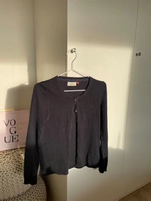 Marinblå kofta från Park Lane, strl 34 - Marinblå, klassisk kofta från Park Lane i storlek 34. Rund halsringning, långa ärmar och knäppning med bruna knappar framtill. Mjuk och tunn stickad bomullskvalitet som är enkel att matcha med olika outfits.