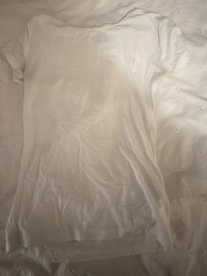 Vit t-shirt från Gina Tricot XS - En enkel och klassisk vit t-shirt från Gina Tricot i storlek XS. T-shirten har korta ärmar och är gjord i mjuk bomull som känns skön mot huden. Perfekt att matcha med jeans eller shorts för en clean och fräsch look.