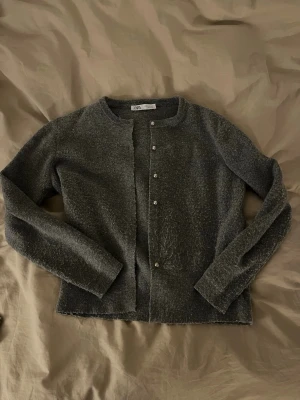 Grå kofta från Zara med silverknappar - Mysig grå kofta från Zara i storlek L. Koftan har en rund halsringning och är långärmad med en stickad struktur. Framsidan pryds av fem blanka silverknappar( OBS EN KNAPP SAKNAS ) 🩶