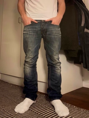 Acne blå jeans med straight fit - Riktigt snygga jeans från Acne i mörkblå denim (W29, L32) med cool tvätt och worn känsla. Ger riktiga archive/vintage vibbar. Skön passform och sitter riktigt bra på (straight fit). Modellen är 180 och väger 72 kg. Säljer för 849kr (nypris ca 1600kr).