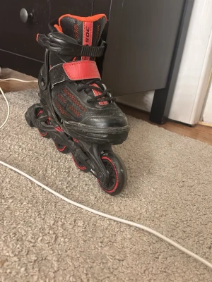 Svart och röd inlines från SOC - Säljer ett par snygga inlines från SOC i svart och rött med coola detaljer. Skon har snörning, kardborreband och extra spänne för bra passform. Hjul och ram är svarta med röda inslag, perfekt för dig som gillar fart och action.
