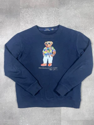 Vintage polo ralph lauren björn tröja - Säljer en vintage Ralph Lauren sweater i klassisk stil. 🧵 Märke: Ralph Lauren 👕 Storlek: M 🎨 Färg: Navy/mörkblå 📌 Design: Klassisk vintage-tröja med bjön tryck 📍 Skick: Mycket bra, se bilder!  Beskrivning: • Tidlös vintage-design från Ralph Lauren • Bekväm och varm – perfekt för höst och vinter • Klassisk passform med stilrena detaljer • Inga fläckar, noppor eller skador (kontrollera bilder) • Lätt att matcha med jeans, chinos eller över skjorta