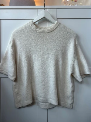 Vit stickad tröja från Gina Tricot - Säljer en vit stickad tröja från Gina Tricot i storlek XS. Tröjan har korta ärmar, rund hals och ribbade detaljer vid hals, ärmslut och nederkant. 