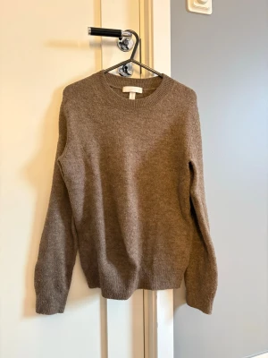 Brun stickad tröja från H&M XS - Fin brun stickad tröja från H&M i storlek XS. Tröjan har rund hals, ribbade muddar vid ärmslut och nederkant samt långa ärmar 