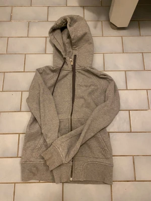 En söt hoodie  - En fin grå och sött hoodie för tjejer med storlek S och den passar till många stilar och har Peak Performance märket på den 