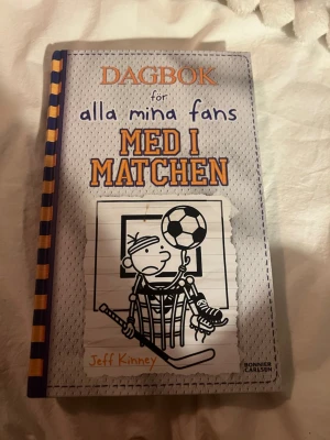 Dagbok för alla mina fans: Med i matchen - Följ Greg Heffley när han försöker ta sig igenom sportens utmaningar och pinsamheter! Med humor och roliga illustrationer är detta en perfekt bok för dig som gillar sport, skratt och att läsa om vardagliga äventyr. Passar dig som vill ha en lättläst och underhållande bok.