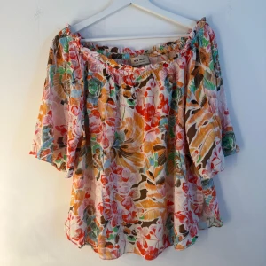 Mos mosh - Färgglad blus med ett blommigt mönster. Den har en smockad halsringning och halvlånga ärmar. Blusen har en lös passform. Storlek M. Nypris runt 1500kr