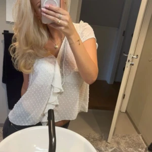 Vit prickig blus med volang - Söt vit blus med små prickar och volang framtill. Knappast använd, storlek xs passar även s