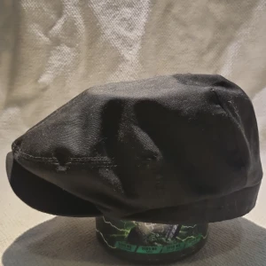 Svart keps Fraser Sr. från CTH Ericson - Snygg svart keps i klassisk modell från CTH Ericson, stil Fraser Sr. Kepsen är tillverkad i 100% bomull och har en mjuk, rundad form med kort skärm. Diskret logga bak med årtalet 1885. Perfekt för dig som gillar tidlös och clean stil.