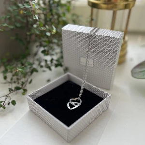 Halsband Edblad med dubbla hjärtan - Snyggt halsband från Edblad i silverfärgad metall med två sammanlänkade hjärtan som hänge. Det ena hjärtat är dekorerat med en liten gnistrande sten. Kedjan är klassisk och passar perfekt till dig som gillar stilrena smycken med en romantisk touch. #edblad #halsband