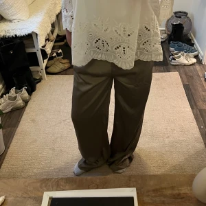 Olivgröna vida byxor i satin - Snygga olivgröna byxor med vid passform och lätt glansigt satintyg. Byxorna har en avslappnad look och faller snyggt längs benen. Perfekta för dig som gillar en loose och trendig stil.