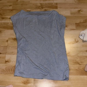 Ljusblå topp från 157 i XS - Aldrig använd Enkel och stilren ljusblå topp från 157 i storlek XS. Toppen har en rak och loose passform med ärmlös design och rund halsringning. Perfekt att matcha med jeans eller kjol för en avslappnad look.