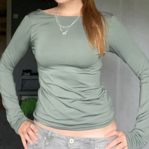 Grön långärmad topp från Weekday - Snygg ljusgrön långärmad topp från Weekday med tight passform och rundad öppen rygg. Tillverkad i mjukt och stretchigt material som sitter skönt på kroppen. Perfekt att styla med jeans eller kjol för en trendig look.