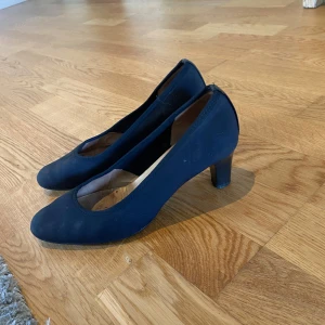 Vintage Svarta klackar/ pumps från Peter Kaiser - Snygga vintage pumps från Peter Kaiser med rund tå och låg klack. Skorna har en klassisk och stilren design i mocka-liknande material och är perfekta för dig som gillar en tidlös look. Insidan är i ljust skinn för extra komfort. Sulan inuti är sliten men resten av är i mycket bra skick🥰